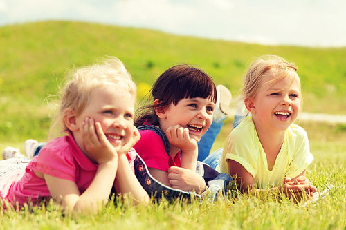 summer, childhood, leisure and people concept - group of happy kids lying on blanket or cover outdoors