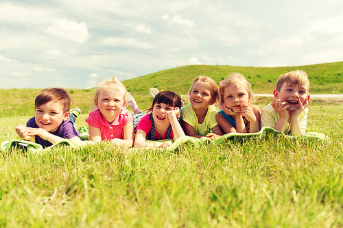 summer, childhood, leisure and people concept - group of happy kids lying on blanket or cover outdoors