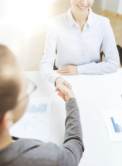 business and office concept - two smiling businesswoman shaking hands in office