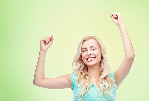 emotions, expressions, success and people concept - happy young woman or teenage girl celebrating victory over green natural background