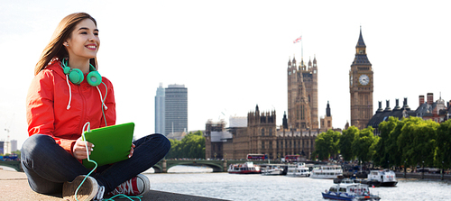 technology, travel, tourism, music and people concept - smiling young woman or teenage girl with tablet pc computer and headphones over london city and big ben tower background