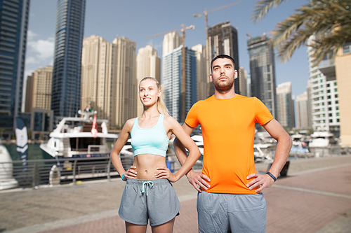 fitness, sport, friendship and healthy lifestyle concept - happy couple exercising over dubai city street background