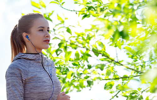 fitness, sport, people, technology and lifestyle concept - happy woman running and listening to music in earphones over green natural background