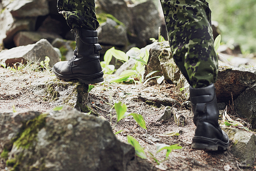 war, hiking, army and people concept - close up of soldier legs climbing on rocks in forest