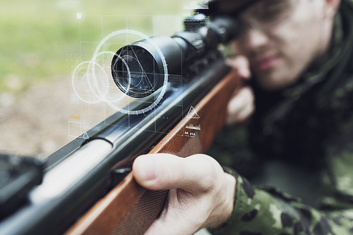 hunting, war, army, technology and people concept - close up of young soldier or sniper holding gun with virtual screen projection and aiming in forest