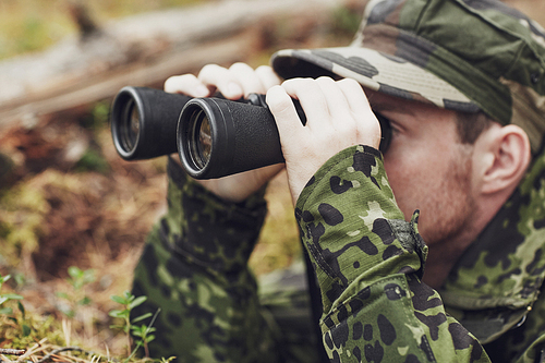 hunting, war, army and people concept - young soldier, ranger or hunter with binocular observing forest