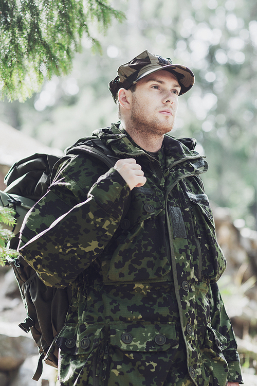 war, hiking, army and people concept - young soldier or ranger with backpack walking in forest
