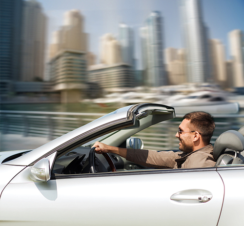 auto business, transport, leisure and people concept - happy man driving cabriolet car over dubai city port background