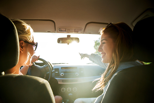 summer vacation, holidays, travel, road trip and people concept - happy teenage girls or young women driving in car