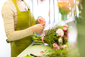 people, business,  and floristry concept - close up of florist woman making bunch at flower shop