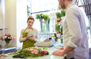 people, shopping, sale, floristry and consumerism concept - happy smiling florist woman with tablet pc computer and man or customer at flower shop