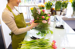 people, business,  and floristry concept - close up of florist woman making bunch at flower shop