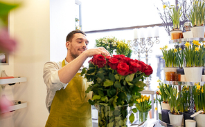 people, business,  and floristry concept - happy smiling florist man with red roses at flower shop