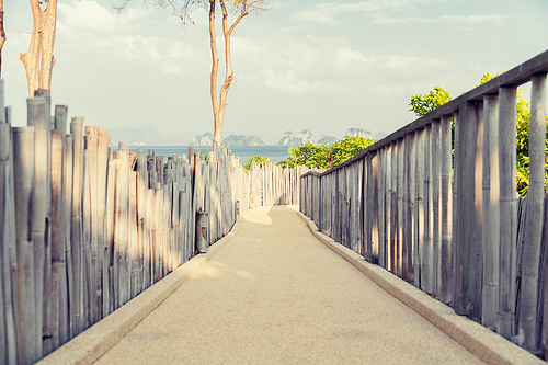 travel, tourism, summer holidays, vacation and leisure concept - road with fence at seaside