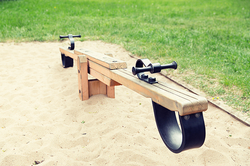 childhood, equipment and object concept - close up of swing or teeterboard on playground outdoors