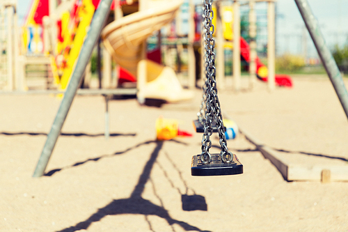 childhood, equipment and object concept - close up of swing on playground outdoors at summer