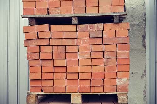 brickwork, construction and building material concept - brown bricks batch on wooden storage tray
