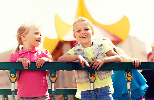 summer, childhood, leisure, friendship and people concept - happy little girls on children playground climbing frame