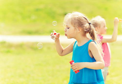 summer, childhood, leisure and people concept - group of little girls blowing soap bubbles outdoors