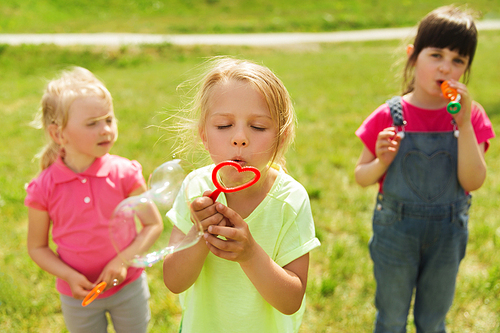 summer, childhood, leisure and people concept - group of kids blowing soap bubbles outdoors