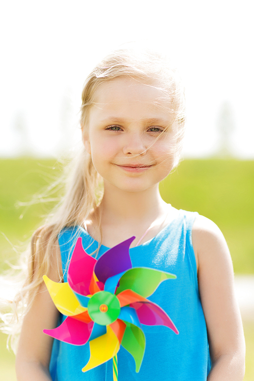 summer, childhood, leisure and people concept - happy little girl with colorful pinwheel toy outdoors