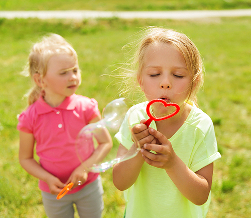 summer, childhood, leisure and people concept - group of kids blowing soap bubbles outdoors