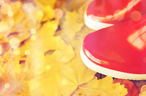 footwear, autumn and season concept - close up of red rubber boots on fallen yellow autumn leaves
