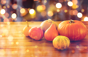 food, , harvest, season and autumn concept - close up of pumpkins on wooden table over holidays lights