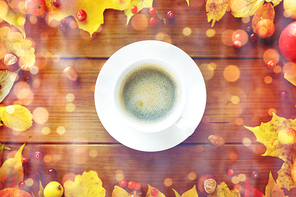 season, drink and morning concept - close up of coffee cup on wooden table with autumn leaves