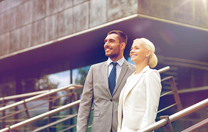 business, partnership, success and people concept - smiling businessman and businesswoman standing over office building