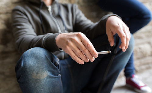 substance abuse, addiction, people and bad habits concept - close up of young man smoking cigarette outdoors