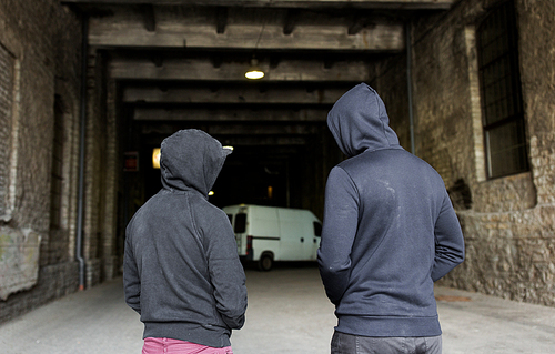 criminal activity, addiction, people and social problem concept - close up of addict men or criminals in hoodies on street