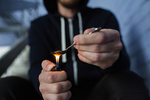 drug use, crime, addiction, substance abuse and people concept - close up of addict with lighter and spoon preparing dose of crack cocaine on street