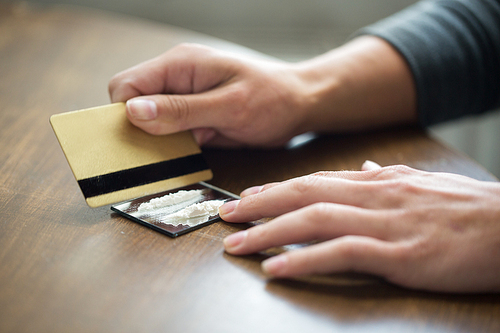 drug use, people, addiction and substance abuse concept - close up of addict hands with crack cocaine drug dose track on mirror and credit card