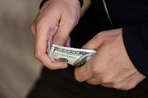 drug trafficking, crime, addiction, people and sale concept - close up of addict or dealer hands with dollar money and dose