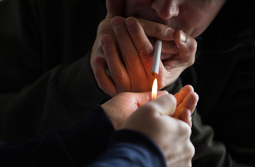 smoking, substance abuse, addiction and bad habits concept - close up of young people lighting cigarette outdoors