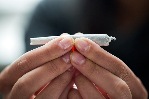 drug use, substance abuse, addiction and people concept - close up of addict hands with marijuana joint