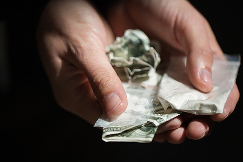 drug trafficking, crime, addiction and sale concept - close up of addict hands with drugs and money