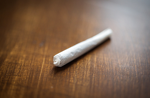 drug use, substance abuse, addiction and smoking concept - close up of marijuana joint or handmade cigarette