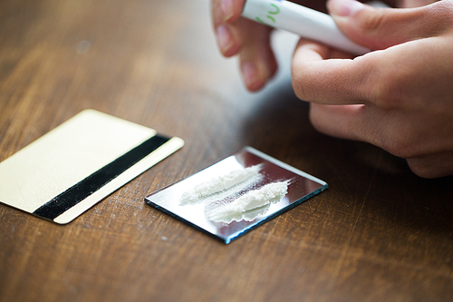 drug use, people, addiction and substance abuse concept - close up of addict hands with crack cocaine drug dose track on mirror, credit card and money roll