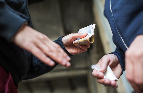 drug trafficking, crime, addiction and sale concept - close up of addict with money buying dose from dealer on street