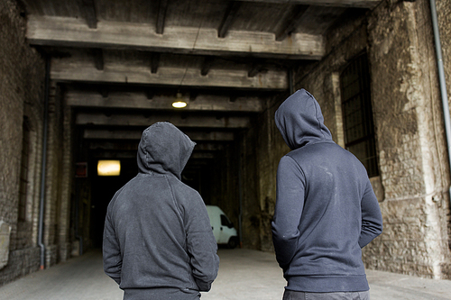 criminal activity, addiction, people and social problem concept - close up of addict men or criminals in hoodies on street