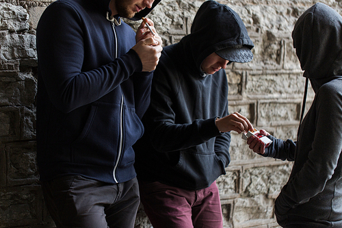 substance abuse, addiction, people and bad habits concept - close up of young smoking cigarettes outdoors