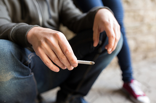 substance abuse, addiction, people and bad habits concept - close up of young man smoking cigarette outdoors