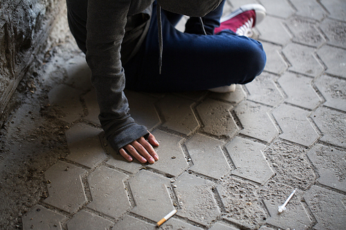 substance abuse, addiction, people and drug use concept - close up of addict woman and used syringes on ground