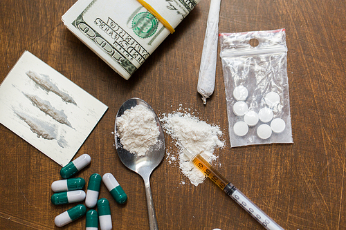 drug use, crime, addiction and substance abuse concept - close up of drugs with  money, spoon and syringe