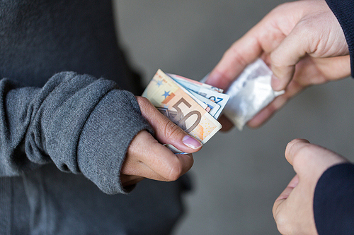 drug trafficking, crime, addiction and sale concept - close up of addict with money buying dose from dealer on street