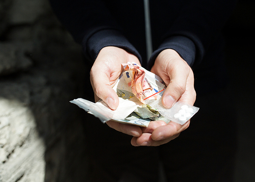 drug trafficking, crime, addiction and sale concept - close up of addict hands with drugs and money