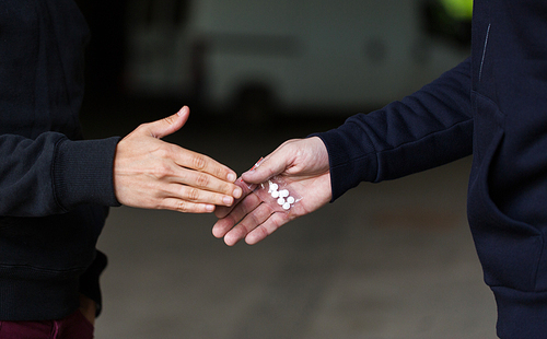 drug trafficking, crime, addiction and sale concept - close up of addict buying dose from dealer