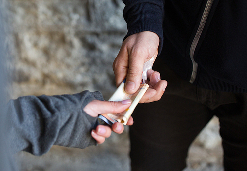 drug trafficking, crime, addiction and sale concept - close up of addict with money buying dose from dealer on street